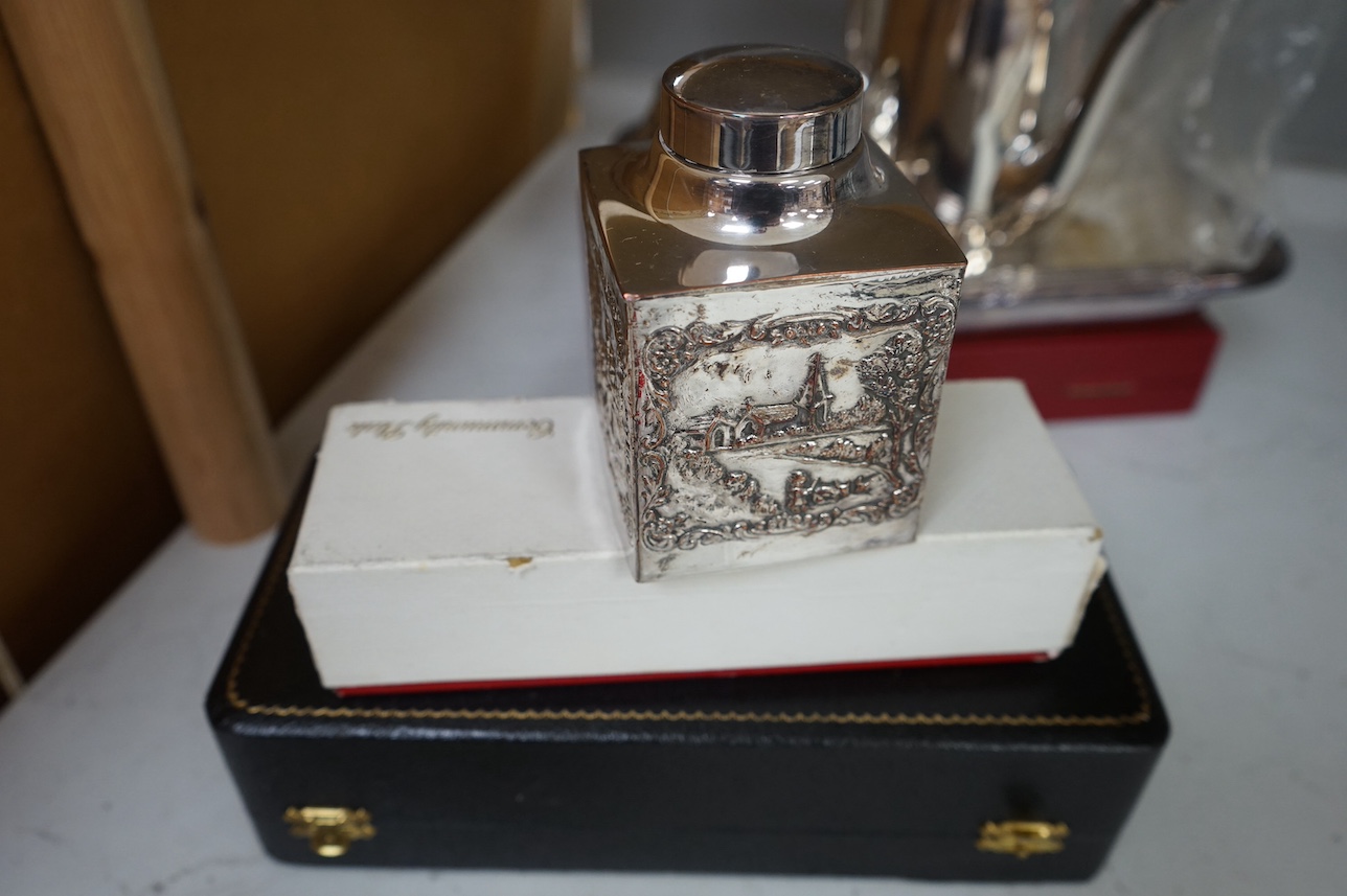 A George V silver cigarette box and assorted plated ware to include a cased cruet, a modern silver wine coaster and an embossed Dutch style tea caddy, largest 23cm wide. Condition - varies